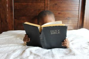 Photo of a child reading an old worn-out Bible.