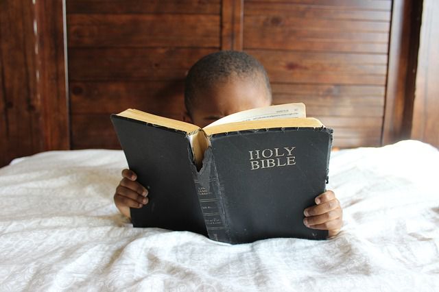 Photo of a child reading an old worn-out Bible. 